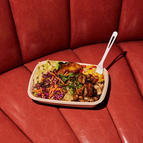 Jrk! Jamaican jerk chicken bowl with rice, plantains, slaw, and salsa on a red booth.