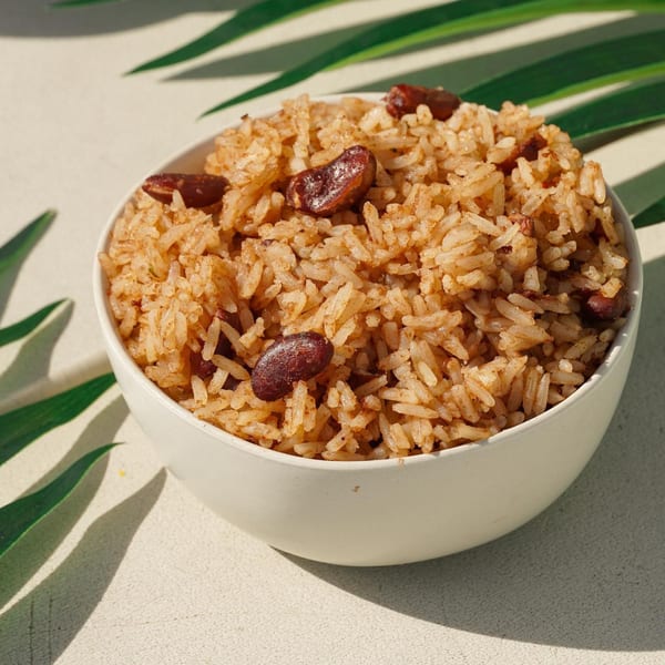 A white bowl filled with Jrk! Jamaican rice and peas, with palm leaves in the background.